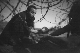 Hope for a new life. A man passes a baby through the fence at the Hungarian-Serbian border in Röszke, Hungary, 28 August 2015. World Press Photo 2015. © Warren Richardson